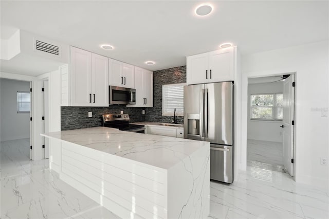 kitchen with stainless steel appliances, a peninsula, a sink, visible vents, and marble finish floor