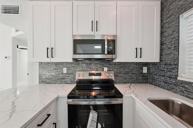 kitchen featuring appliances with stainless steel finishes, visible vents, backsplash, and white cabinetry