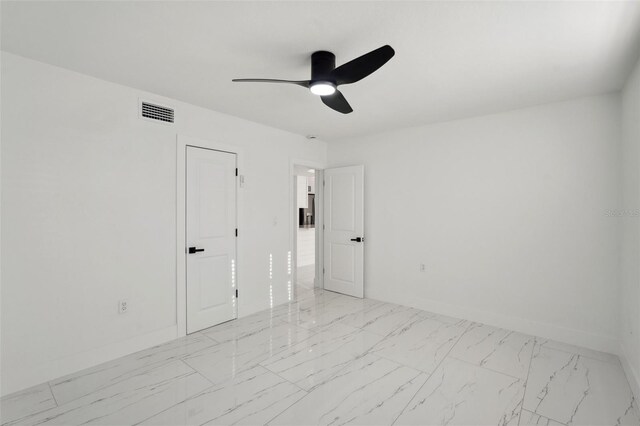 empty room with marble finish floor, baseboards, visible vents, and a ceiling fan