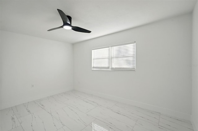 empty room featuring marble finish floor, ceiling fan, and baseboards
