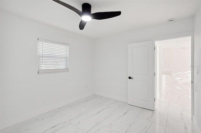 spare room featuring ceiling fan, marble finish floor, and baseboards