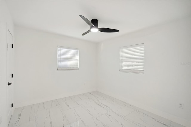 empty room featuring ceiling fan, marble finish floor, and baseboards