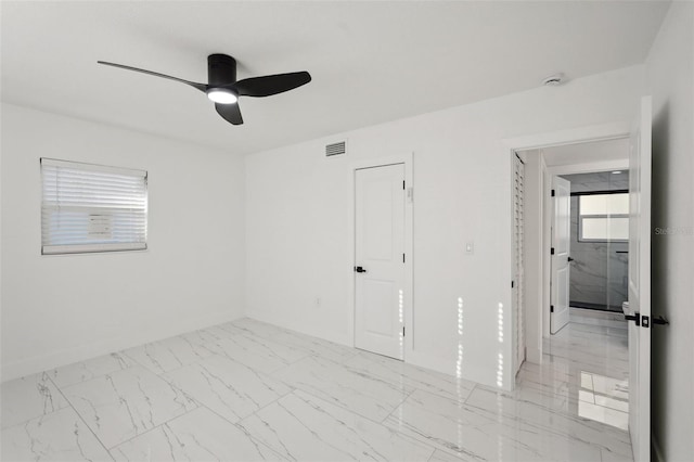 unfurnished room featuring baseboards, marble finish floor, visible vents, and a ceiling fan