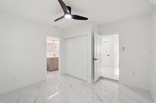unfurnished bedroom with marble finish floor, a closet, ensuite bath, and baseboards