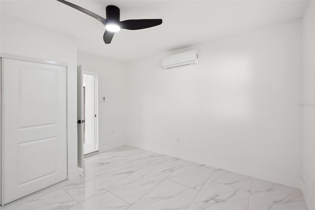 spare room with marble finish floor, a wall unit AC, a ceiling fan, and baseboards