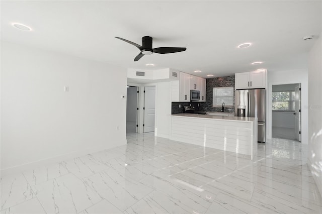 unfurnished living room with marble finish floor, visible vents, a ceiling fan, a sink, and baseboards