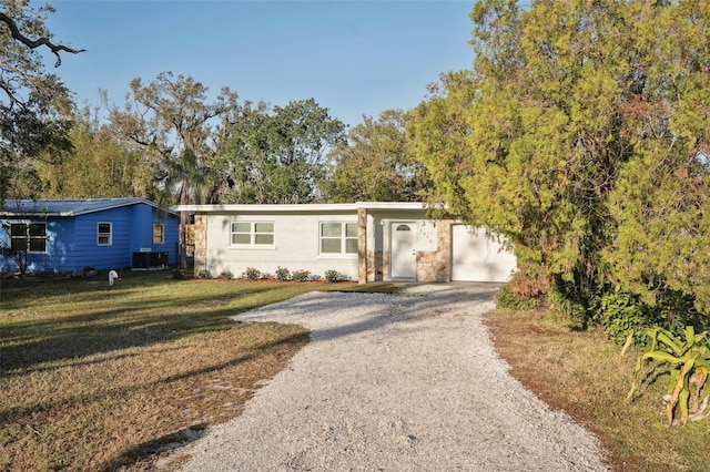 ranch-style home with a front yard, driveway, and central AC unit