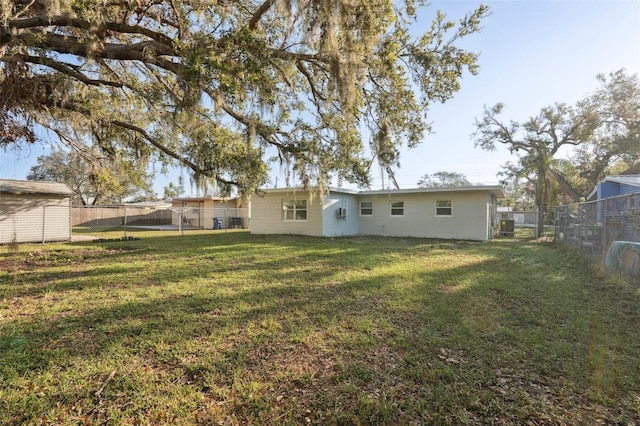back of property with a lawn, a fenced backyard, a gate, a storage unit, and an outdoor structure