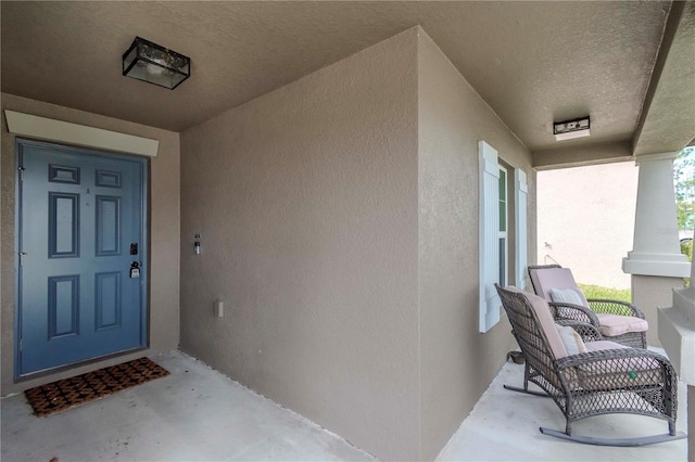 property entrance featuring a porch and stucco siding