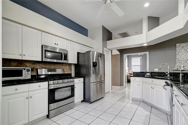 kitchen with light tile patterned floors, decorative backsplash, stainless steel appliances, white cabinetry, and a sink