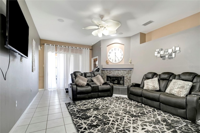 living room featuring light tile patterned floors, visible vents, baseboards, a ceiling fan, and a glass covered fireplace