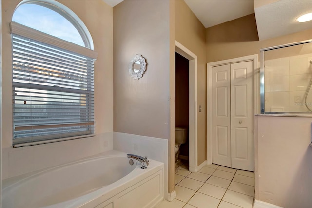 bathroom featuring baseboards, toilet, a shower with shower door, tile patterned flooring, and a bath