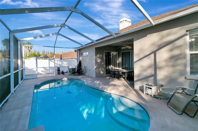 view of swimming pool with glass enclosure, a patio area, a ceiling fan, and a fenced in pool