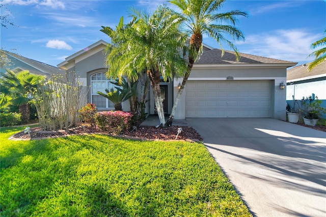 view of front of home with a front lawn, driveway, an attached garage, and stucco siding