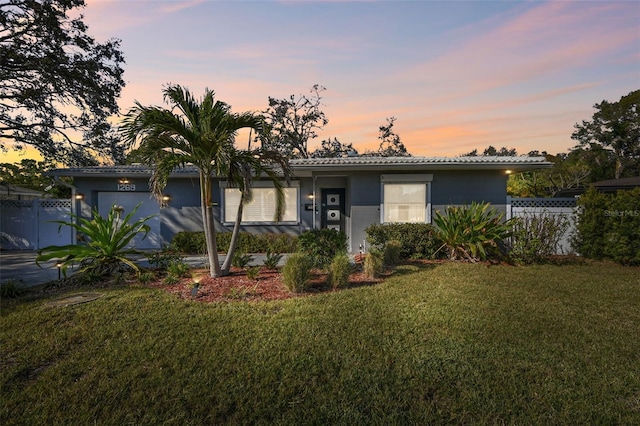 single story home featuring a garage, a tile roof, a front yard, and fence