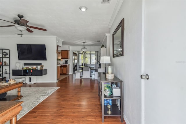 living area with dark wood finished floors, baseboards, a ceiling fan, and ornamental molding