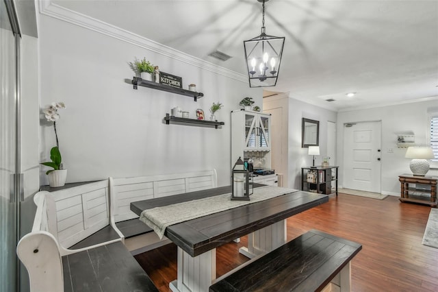 dining area with a chandelier, visible vents, crown molding, and wood finished floors