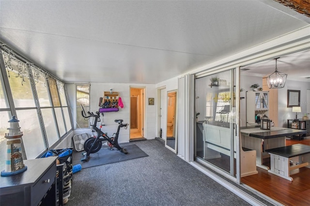 workout area with a notable chandelier, a textured ceiling, and carpet