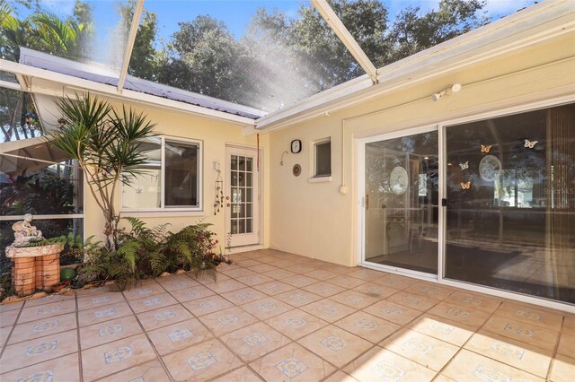 1549 San Christopher Dr, Dunedin, FL 34698 - back of house featuring solar panels, stucco siding, glass enclosure, a patio area, and metal roof