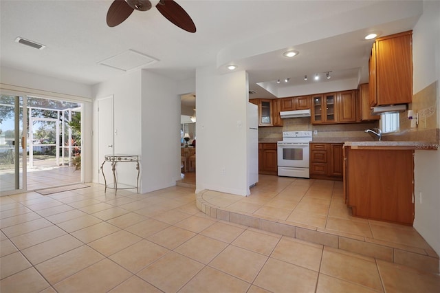 1549 San Christopher Dr, Dunedin, FL 34698 - kitchen with light tile patterned floors, under cabinet range hood, white appliances, visible vents, and brown cabinetry