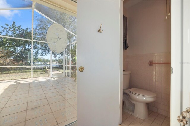 1549 San Christopher Dr, Dunedin, FL 34698 - bathroom with a healthy amount of sunlight, tile walls, toilet, and tile patterned floors