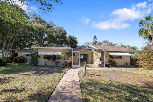 1549 San Christopher Dr, Dunedin, FL 34698 - view of front facade featuring a lanai, a front lawn, and stucco siding