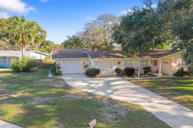 1549 San Christopher Dr, Dunedin, FL 34698 - ranch-style home with stucco siding, concrete driveway, a front yard, fence, and a garage