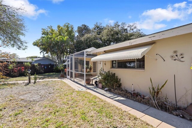 1549 San Christopher Dr, Dunedin, FL 34698 - exterior space with glass enclosure, fence, a lawn, stucco siding, and a patio area