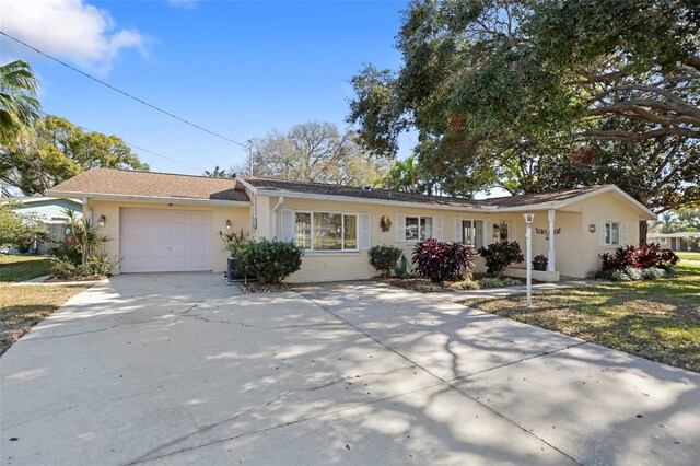 1549 San Christopher Dr, Dunedin, FL 34698 - ranch-style house featuring a garage, driveway, brick siding, and stucco siding
