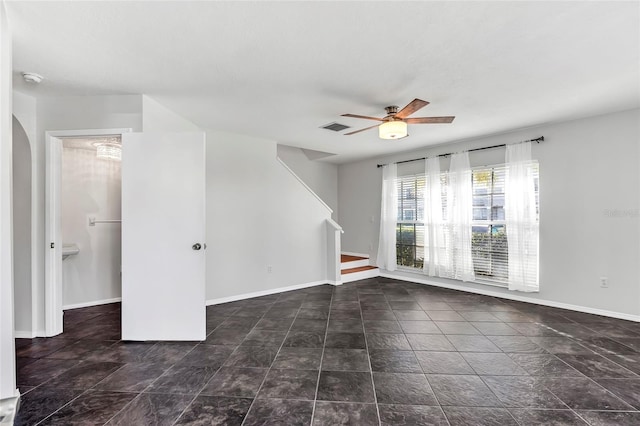 unfurnished living room featuring arched walkways, baseboards, visible vents, ceiling fan, and stairs