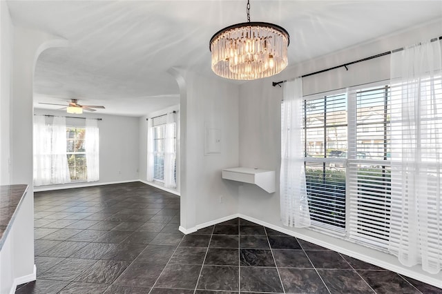 interior space featuring arched walkways, dark tile patterned floors, baseboards, and ceiling fan with notable chandelier