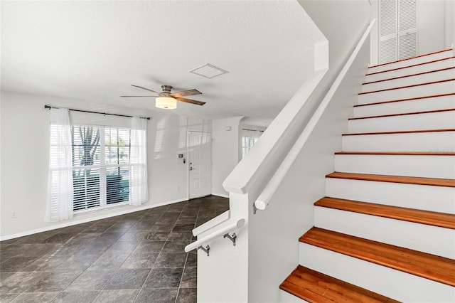 stairs with visible vents, ceiling fan, and baseboards