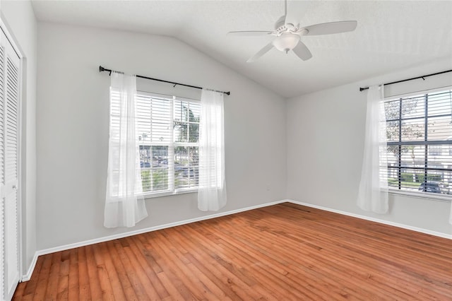 unfurnished room featuring light wood-type flooring, ceiling fan, plenty of natural light, and vaulted ceiling