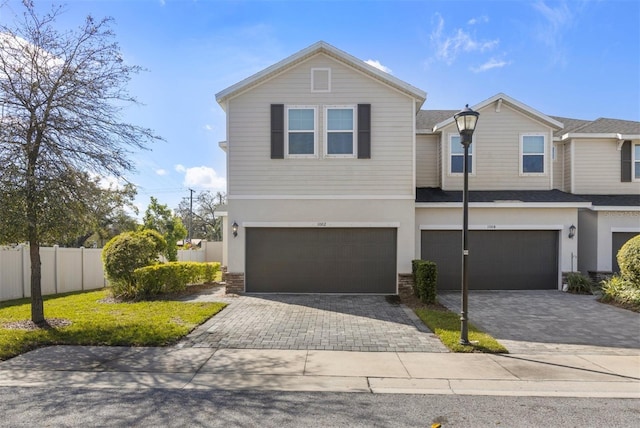 view of front of property featuring a garage, brick siding, fence, decorative driveway, and stucco siding