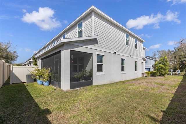 back of property with central AC unit, a lawn, fence, and a sunroom