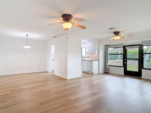 unfurnished living room featuring light wood finished floors, visible vents, and a textured ceiling