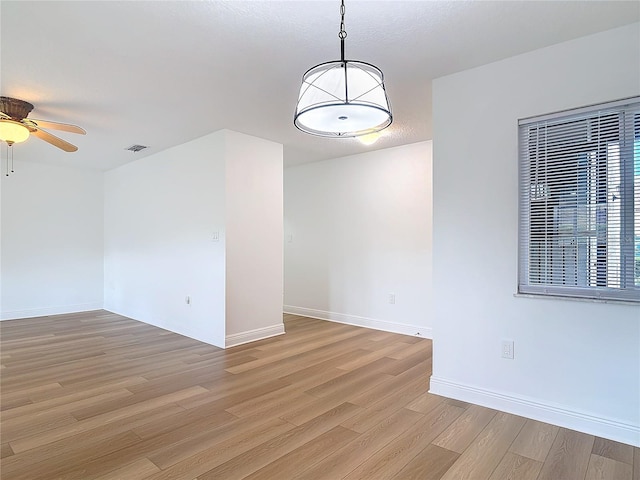 unfurnished room with visible vents, ceiling fan, light wood-style flooring, and baseboards