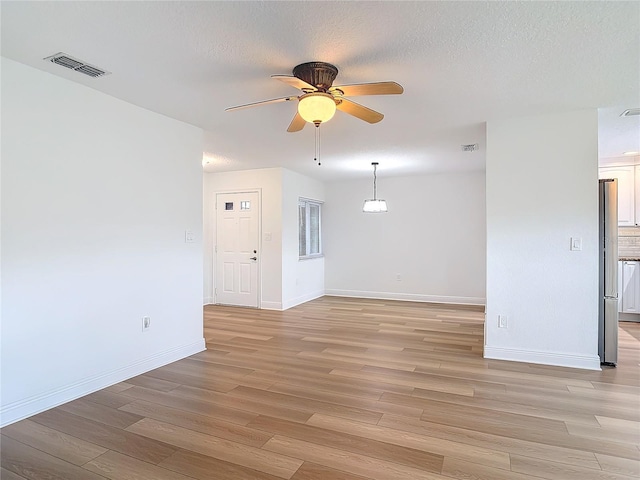 spare room with a ceiling fan, visible vents, a textured ceiling, and light wood finished floors