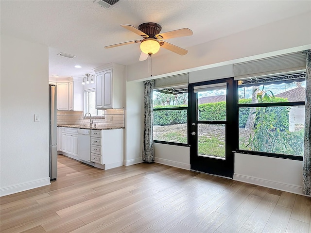 kitchen featuring backsplash, freestanding refrigerator, white cabinets, a sink, and dishwasher