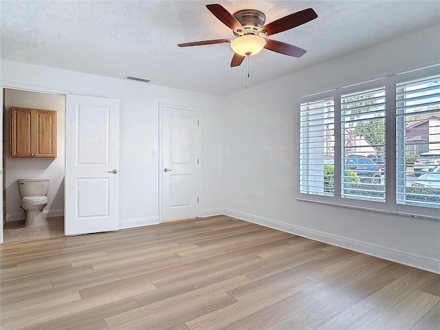 unfurnished bedroom featuring light wood finished floors, baseboards, and a textured ceiling