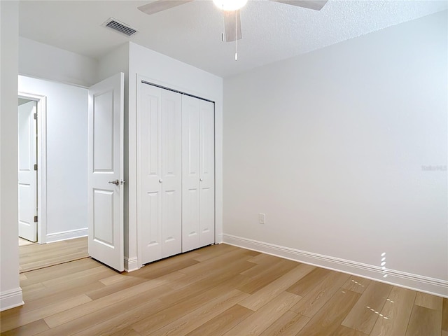 unfurnished bedroom featuring light wood-type flooring, baseboards, visible vents, and a closet