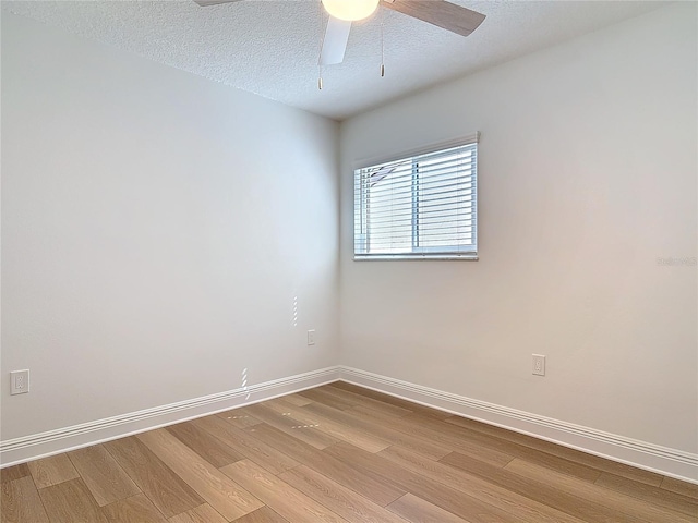 spare room featuring light wood-type flooring, ceiling fan, a textured ceiling, and baseboards