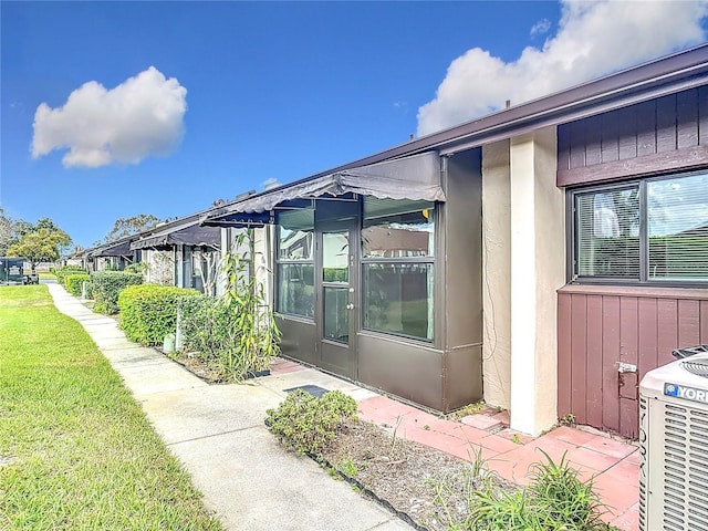 view of side of property featuring a lawn, cooling unit, and stucco siding