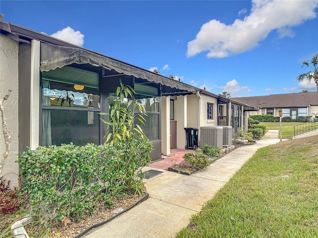 view of side of home featuring a lawn, central AC unit, and stucco siding