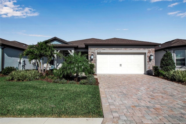 view of front facade featuring a garage, a front yard, decorative driveway, and stone siding