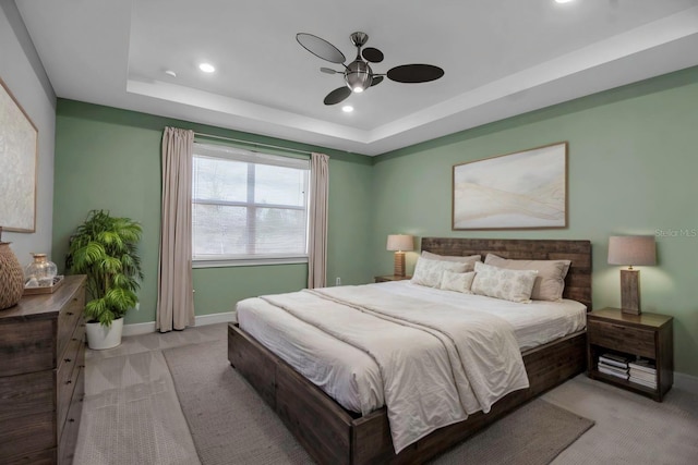 bedroom featuring ceiling fan, baseboards, a raised ceiling, and light colored carpet