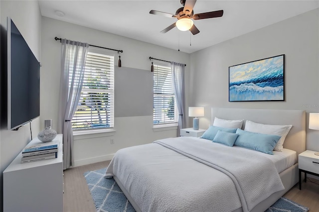 bedroom with light wood-type flooring, ceiling fan, and baseboards