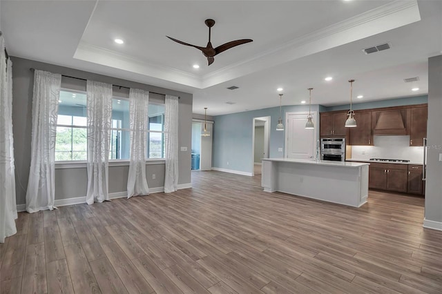 kitchen featuring visible vents, a tray ceiling, light countertops, stovetop, and premium range hood