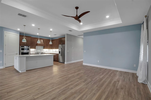 kitchen featuring visible vents, open floor plan, light countertops, appliances with stainless steel finishes, and a tray ceiling