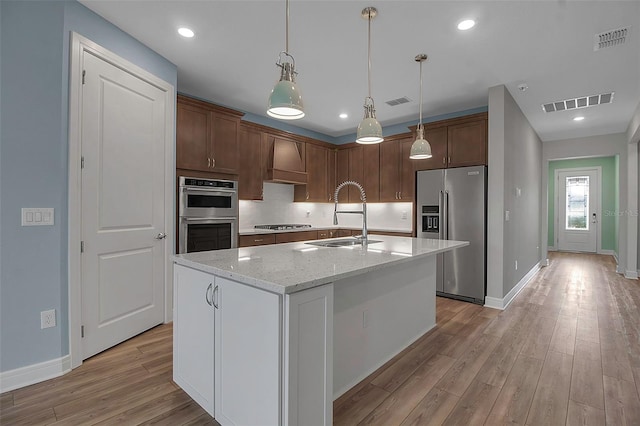 kitchen featuring custom exhaust hood, visible vents, appliances with stainless steel finishes, and a sink